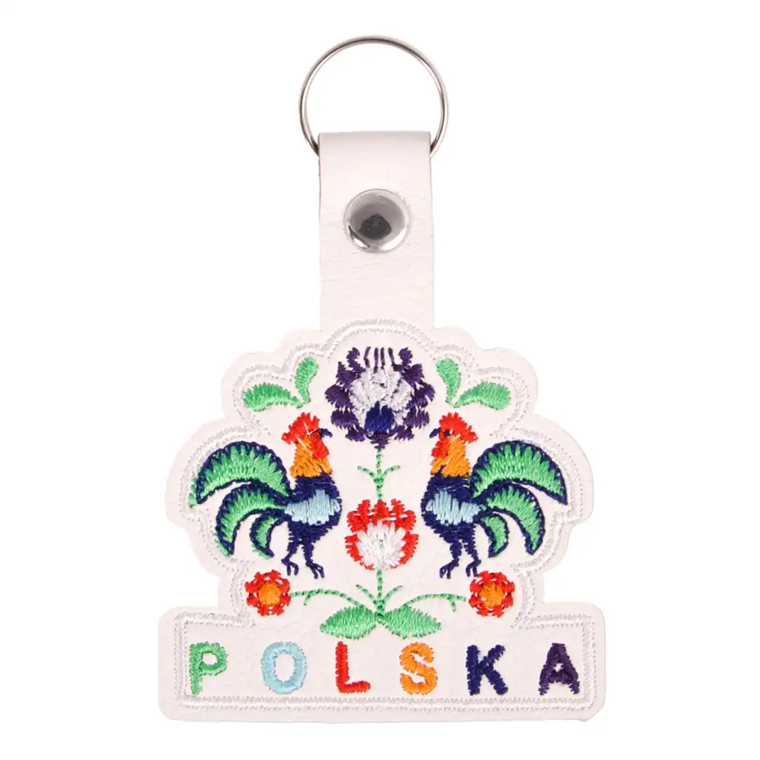 Pendentif brodé avec des motifs de coqs polonais colorés, entouré d'un cadre en métal élégant, parfait pour toutes les occasions.